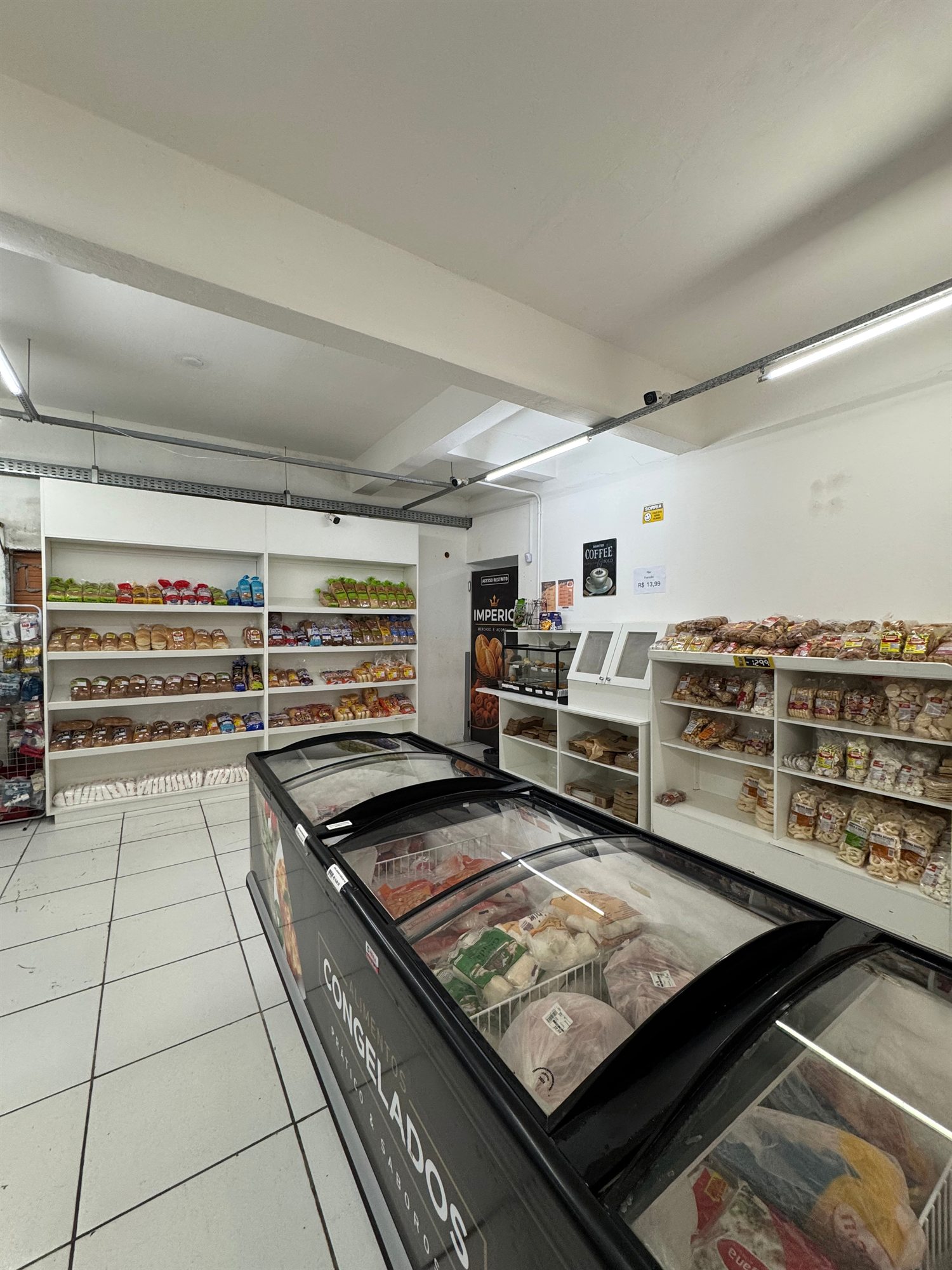Área interna da padaria com pães e produtos organizados nas prateleiras
